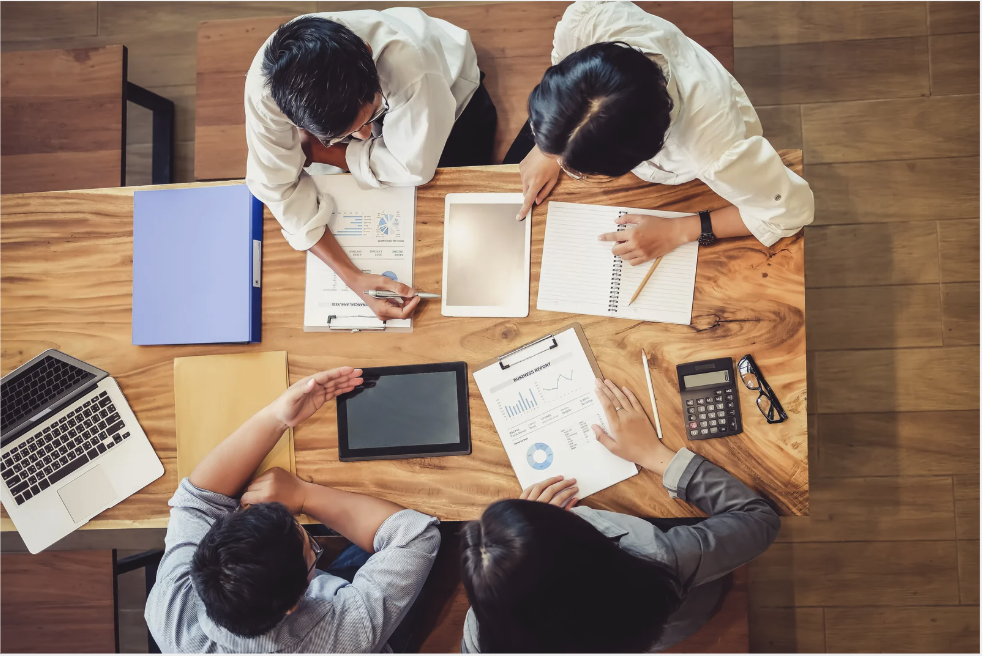 brown table with four people sitting around it, discussing tips for nonprofit success
